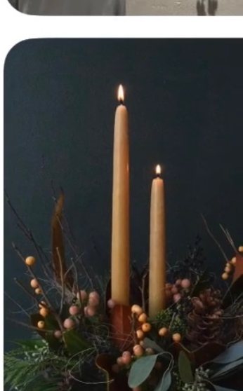 Tall amber candles rising from a winter arrangement